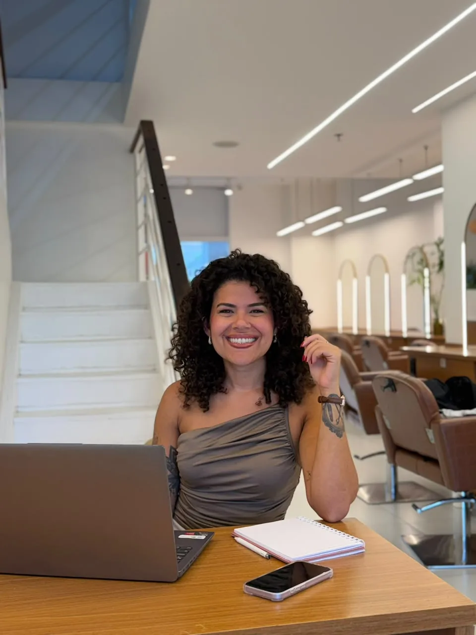 Luize Freire na mesa do salão, com o notebook aberto ao lado do caderno de anotações